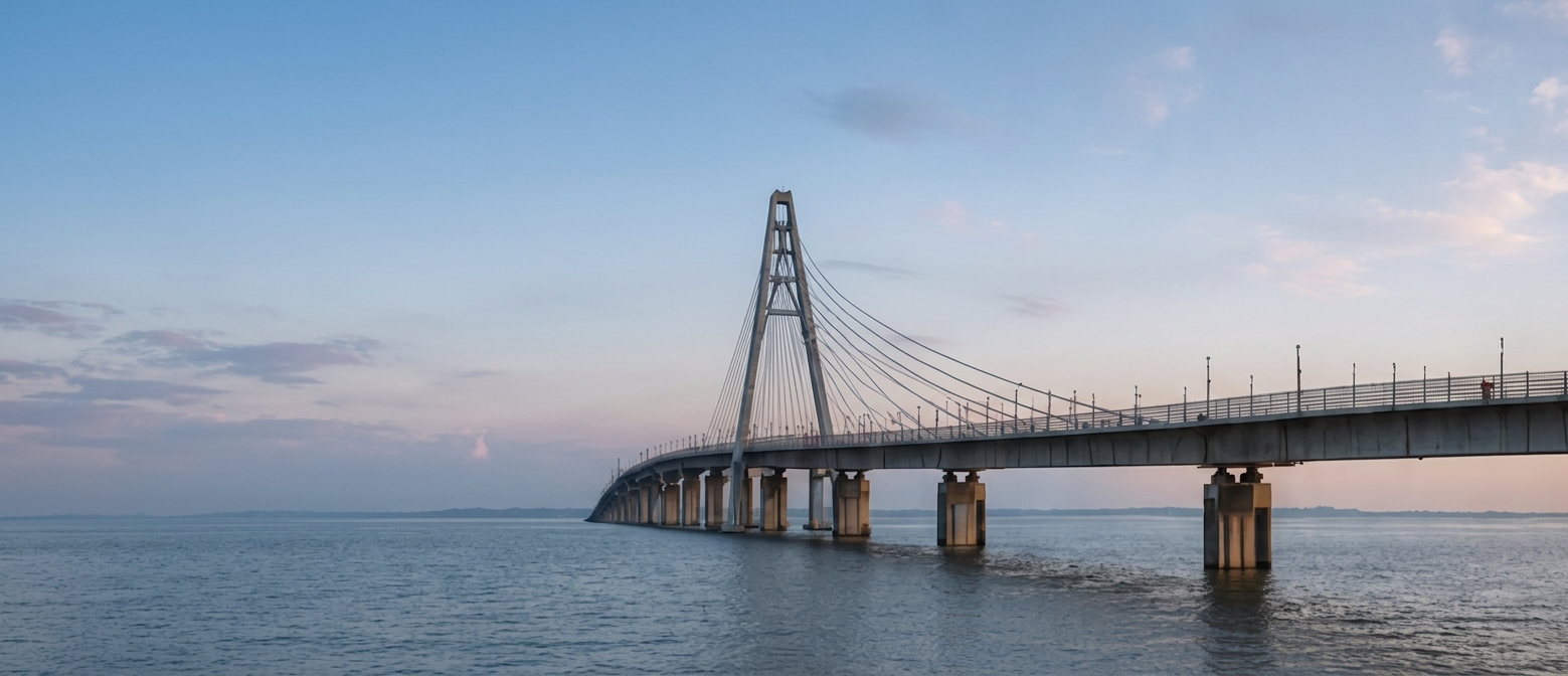 Cable-stayed bridge extending over calm water beneath a pale evening sky
